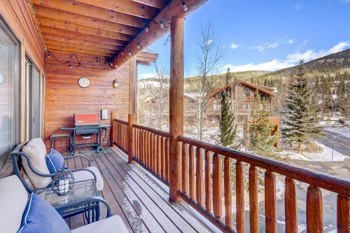 A cozy exterior deck with a wooden railing, comfortable seating, a BBQ grill, and panoramic mountain views. The space is ideal for barbecues or simply unwinding while taking in the natural surroundings.